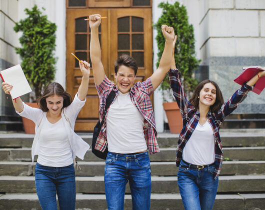 Students cheering in front of the university campus