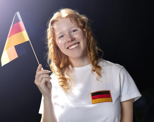 Smiley female student holding german flag in her hand