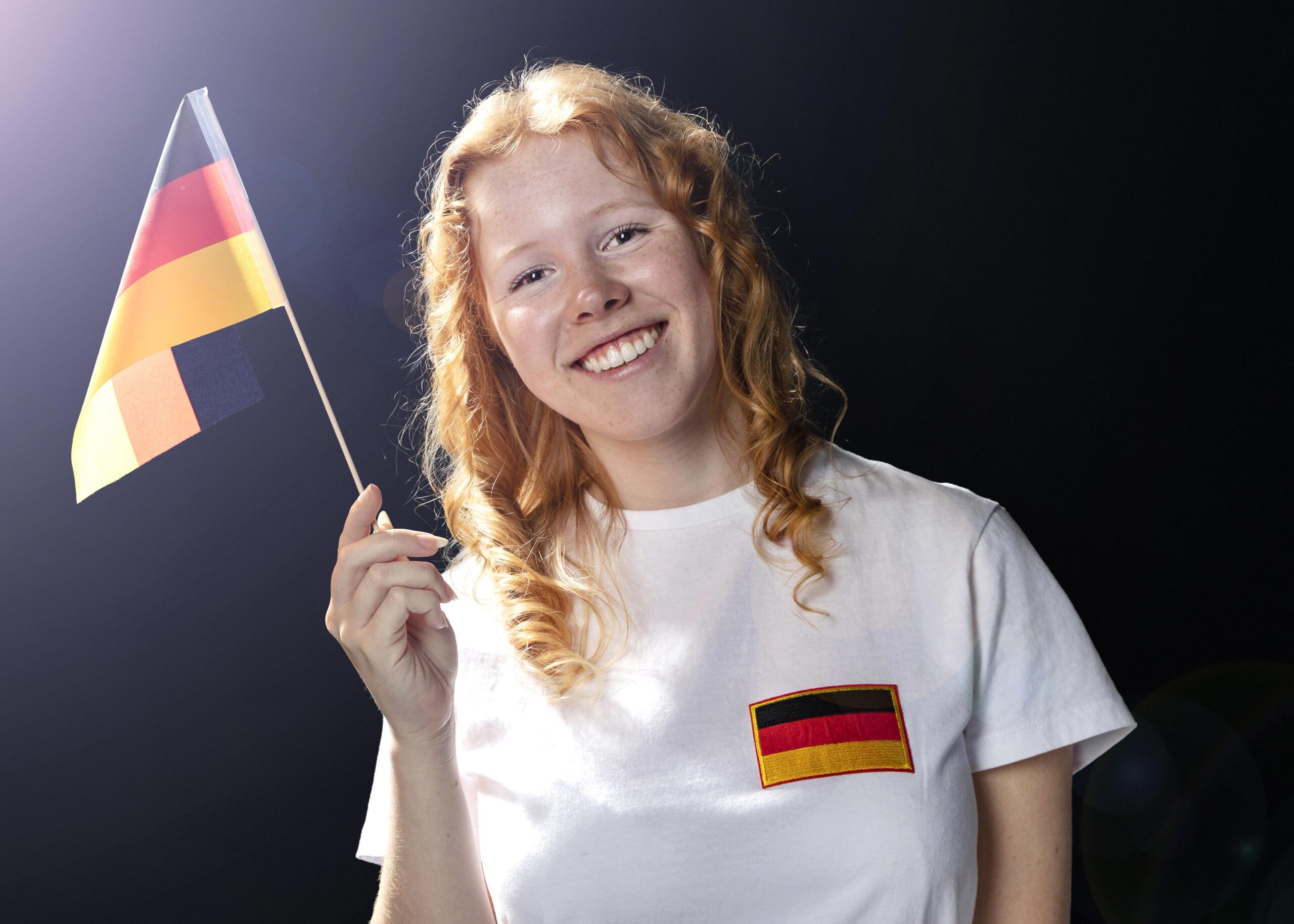 Smiley female student holding german flag in her hand
