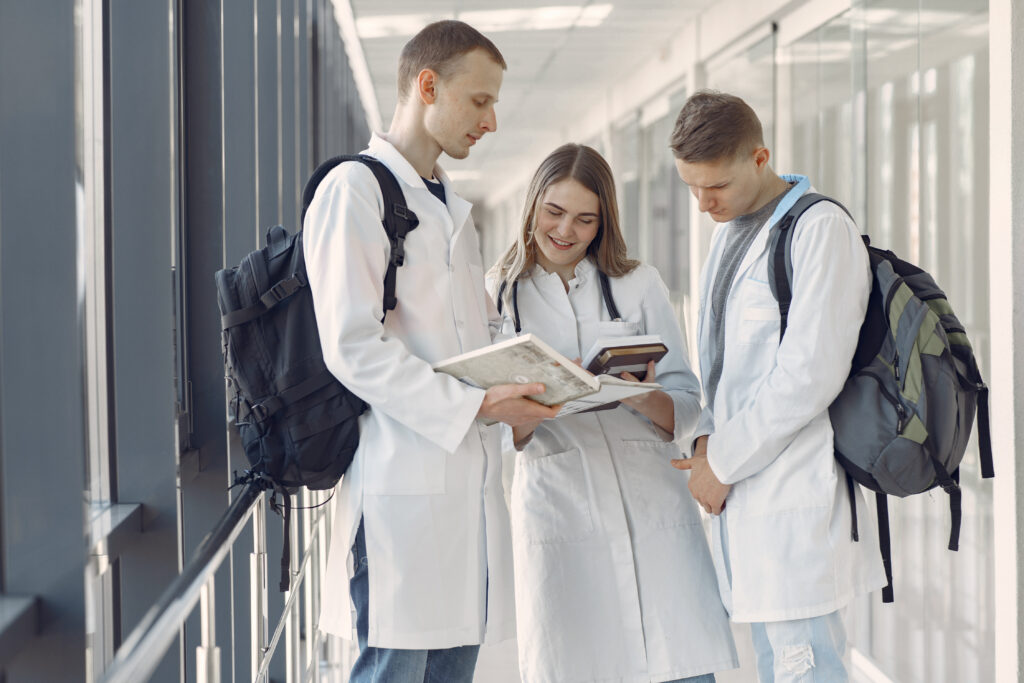 Medical students learning from a book standing at the corridor of hospital