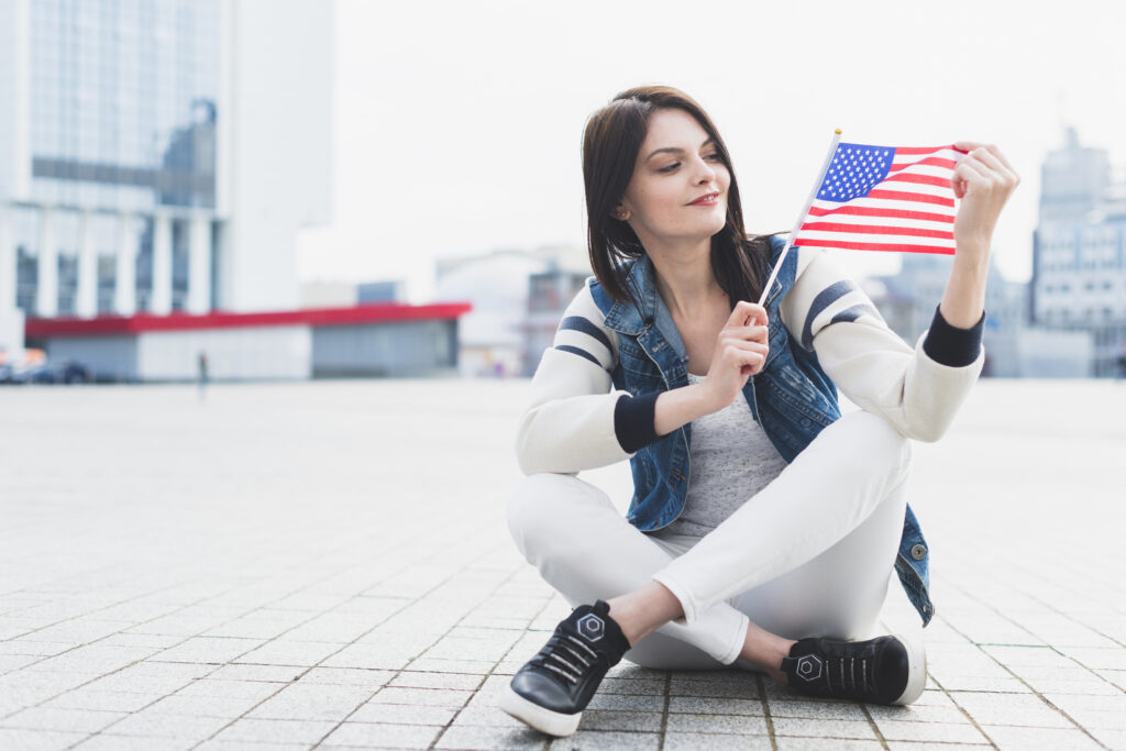 Female student carrying flag of usa in front of university campus