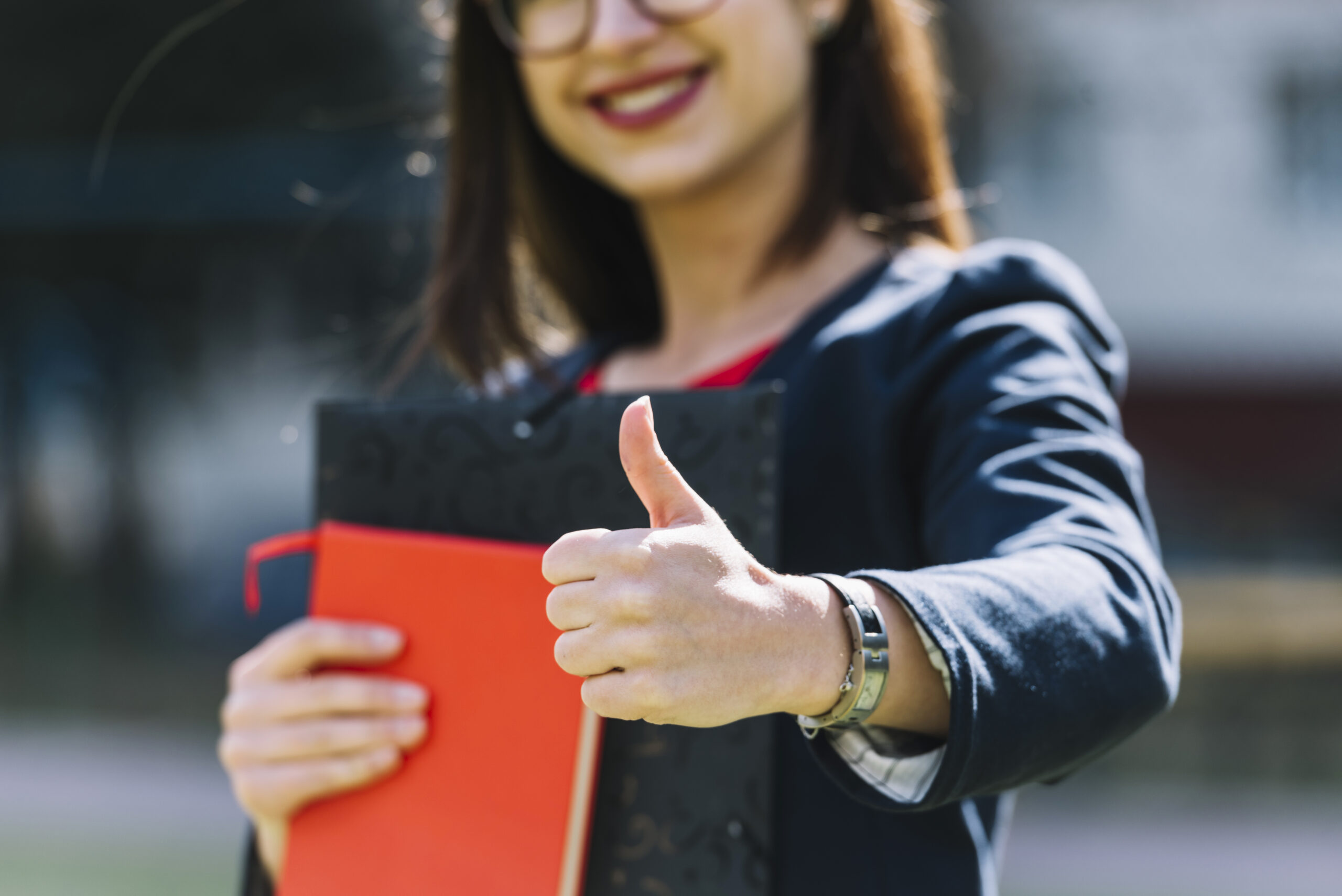Young girl doing thumbs up holding books