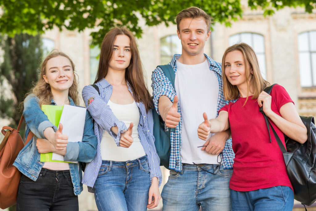 Gropu of students showing off thumb up for scholarships in front of university