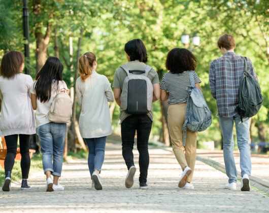 Backside of students walking carrying bags on thier backs