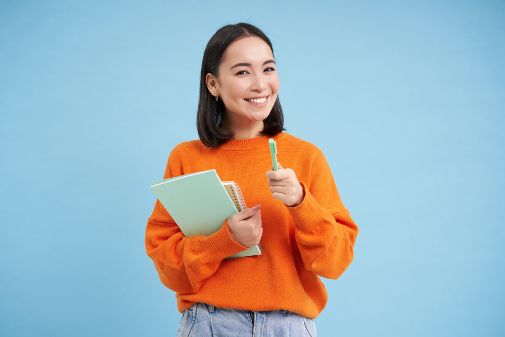 Education female student holding books pointing towards camera