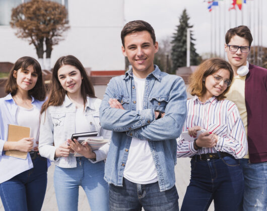 Students with books looking into camera