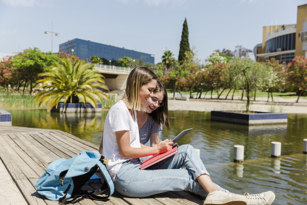 Female students studying near lake in university